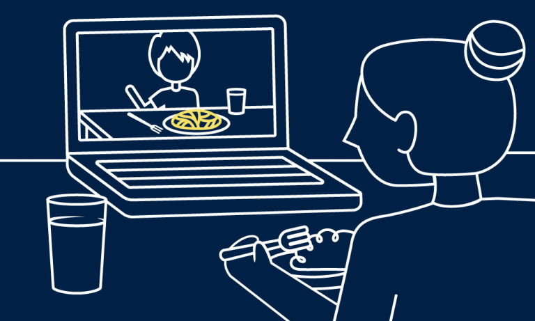A person sits in front of a laptop, appearing to be sharing a meal with someone via a virtual connection