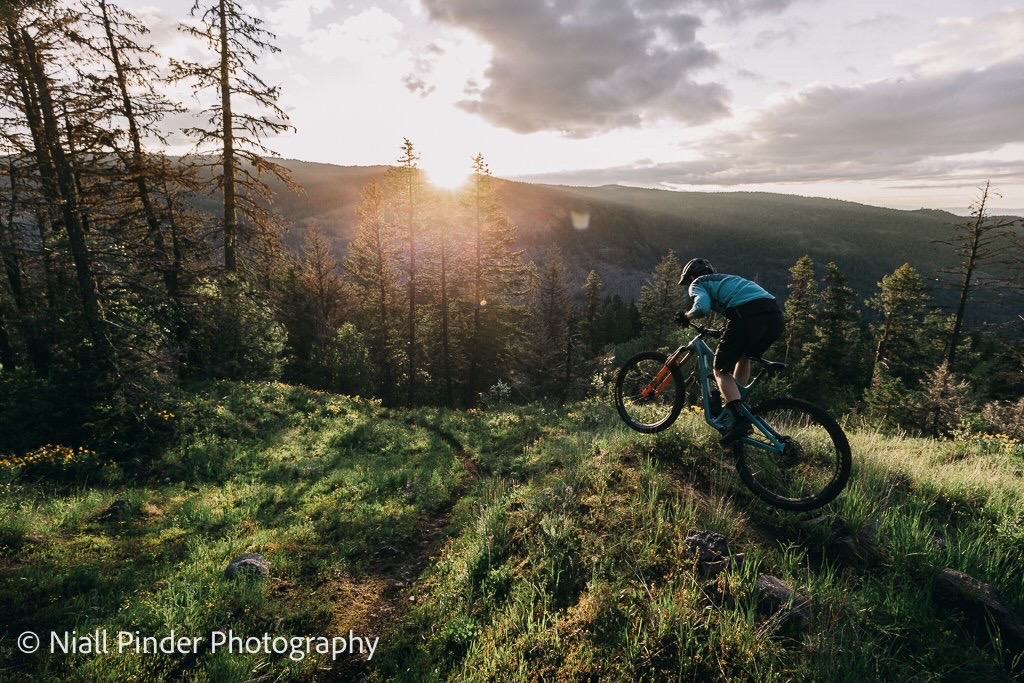 photograph of a student cycling on a hill overlooking the Okanagan Valley. 
