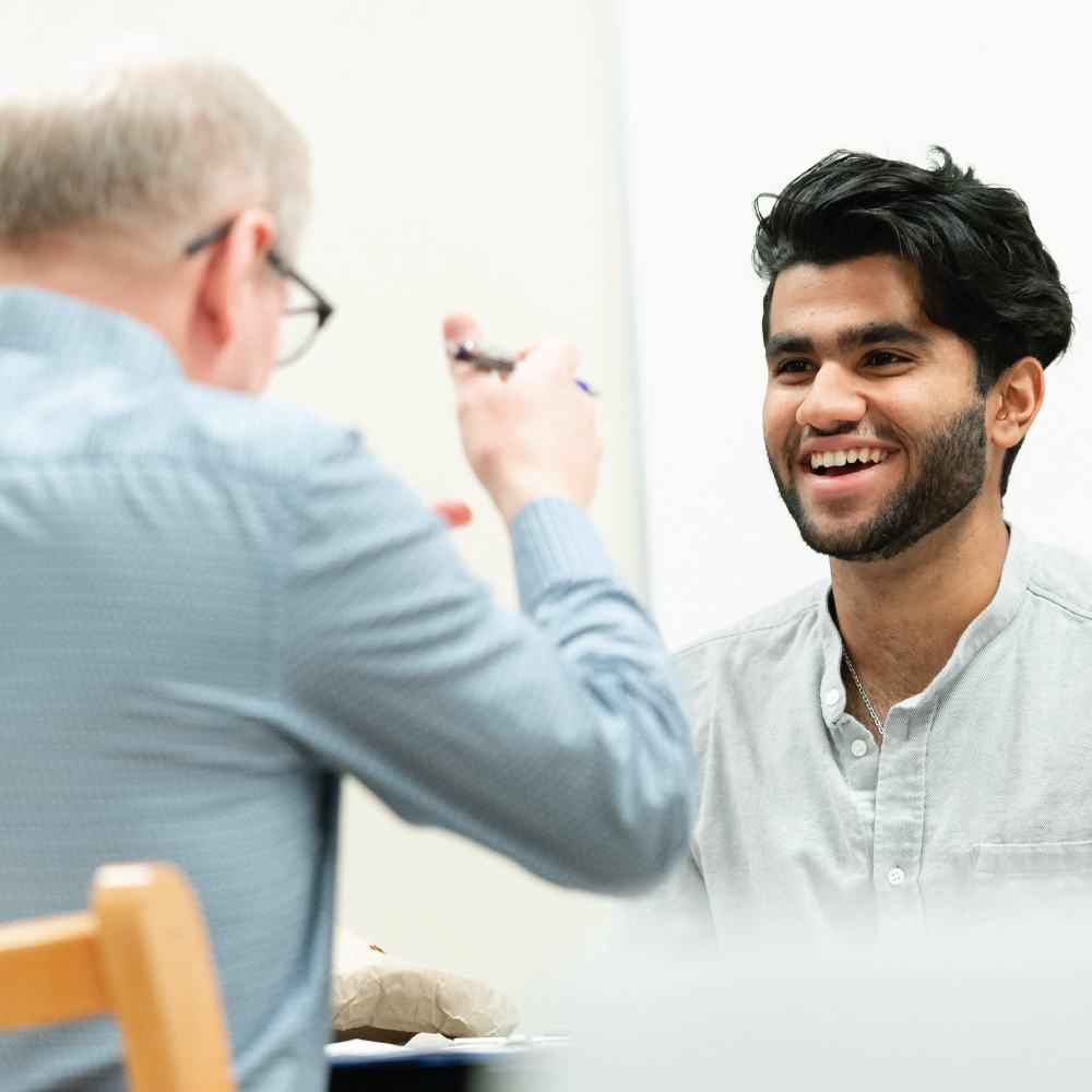 a student laughing and talking with a mentor