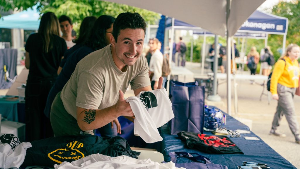 Man holding t-shirt at event and smiling